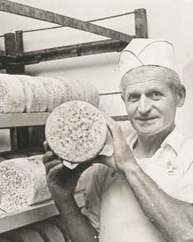 Man holding a whole wheel of organic blue cheese