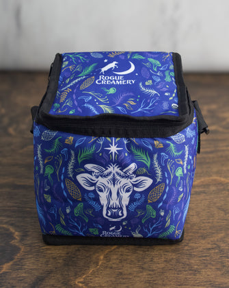 A compact blue insulated cooler bag with a cow’s head and floral design on the front, Rogue Creamery logo above.