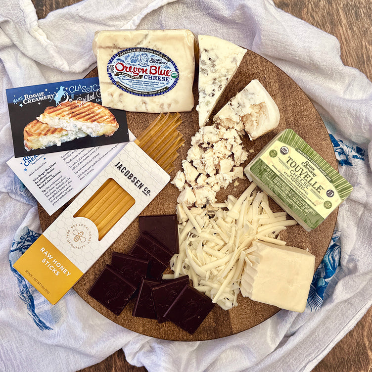 Organic cheeses on cutting board with chocolate and honey sticks