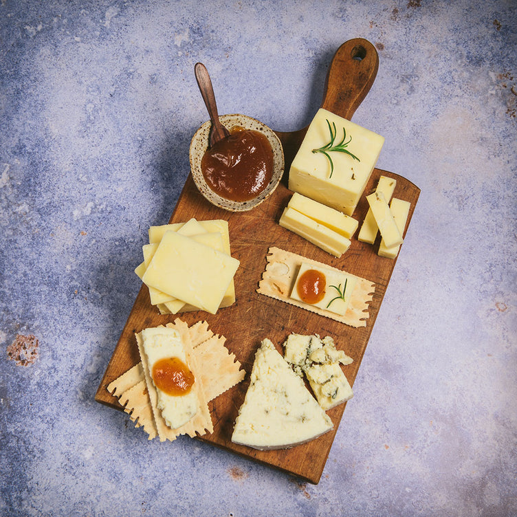 Organic cheese on cutting board with crackers and jams