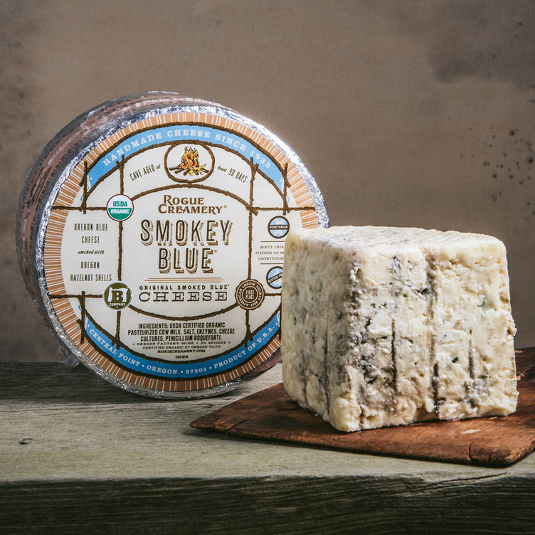 Organic Smokey Blue Cheese whole wheel with wedge on a cutting board