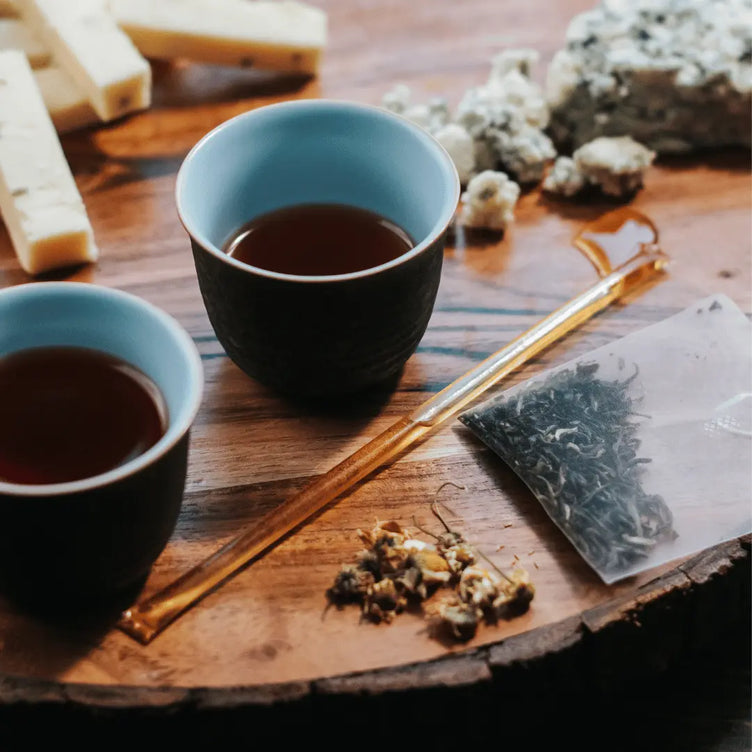 Honey sticks and tea cups with tea leaves on a wooden background