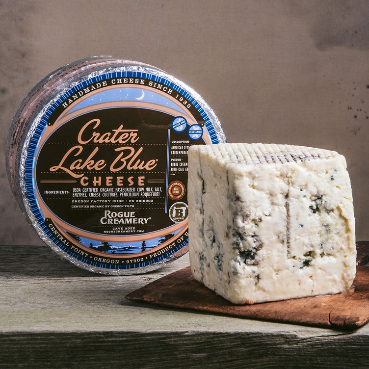 Organic Crater Lake Blue Cheese whole wheel with wedge on cutting board