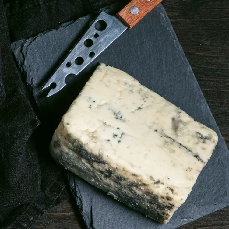organic blue cheese wedge on stone cutting board with knife