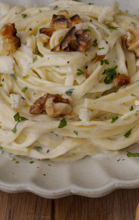 A plate of creamy pasta garnished with walnuts and herbs