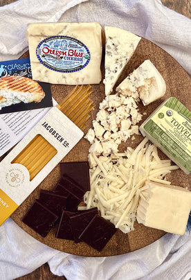 Organic cheeses on cutting board with chocolate and honey sticks