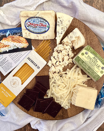 Organic cheeses on cutting board with chocolate and honey sticks