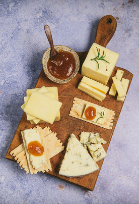 Organic cheese on cutting board with crackers and jams