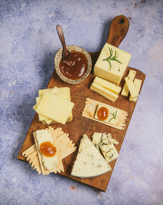 Organic cheese on cutting board with crackers and jams