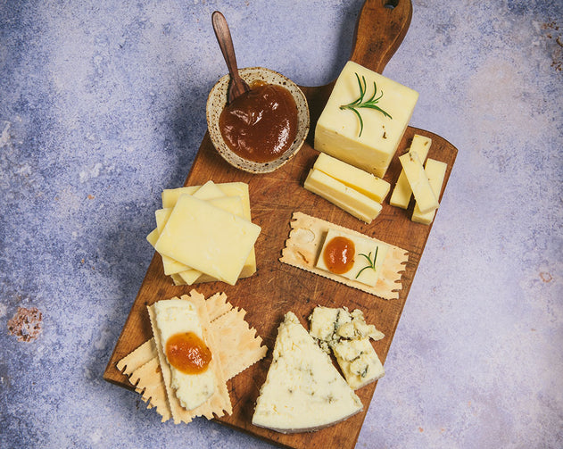 Organic cheese on cutting board with crackers and jams