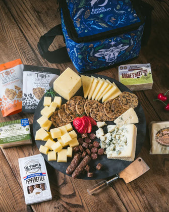 Organic cheeses, crackers, salami, and cooler back on wooden background