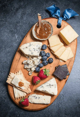 Organic Cheese on cutting board with chocolate, crackers, jam, and fresh fruit