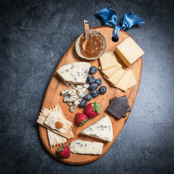 Organic Cheese on cutting board with chocolate, crackers, jam, and fresh fruit