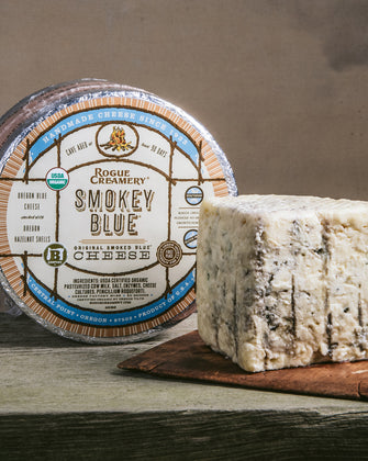 Organic Smokey Blue Cheese whole wheel with wedge on a cutting board