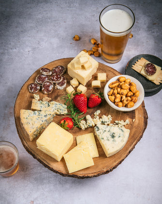 Organic cheeses with salami, beer, and corn nuts on cutting board