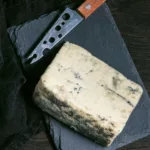Rogue Creamery Organic Oregon Blue Cheese Wedge on stone cutting board with cheese knife