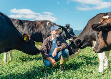 David Gremmels Crouching in a field with cows at Rogue Creamery Dairy