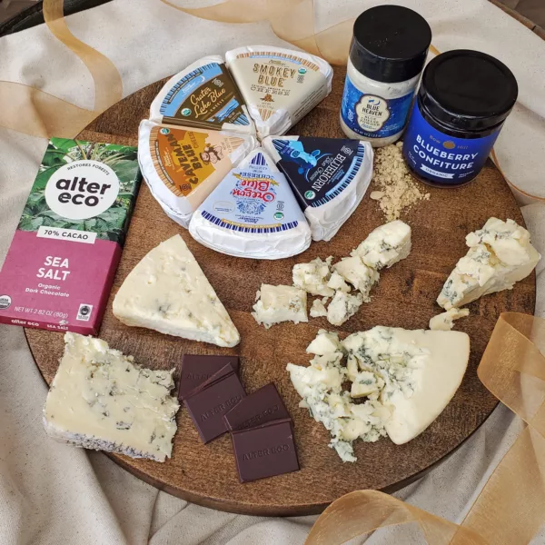 5 Blue Cheese wedges in a circle on a cheese board with blue heaven cheese powder, jam, and a chocolate bar.