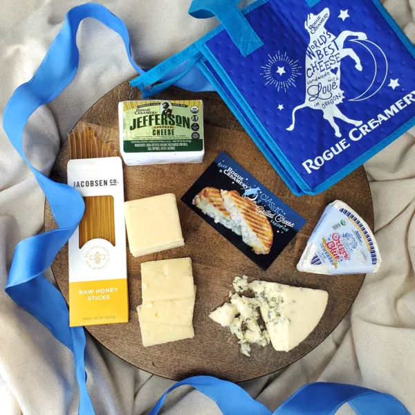 Oregon Blue and Jefferson 1 Year on a cheese board with Rogue Creamery Nellie Bag, Honey Sticks, and Recipe Card