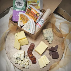 Salami, Chocolate, Chocolate Stout Cheddar, Hopyard Cheddar, Smokey Blue Cheese, and Caveman Blue Cheese spread on a circle cheese board