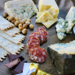 Rogue Creamery Best of the Pacific Northwest Gift Set close up image of Olympia Provisions salami, blue cheese, crackers, hazelnuts, and cheddar cheese