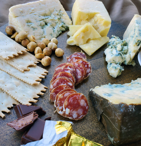 Rogue Creamery Best of the Pacific Northwest Gift Set close up image of Olympia Provisions salami, blue cheese, crackers, hazelnuts, and cheddar cheese