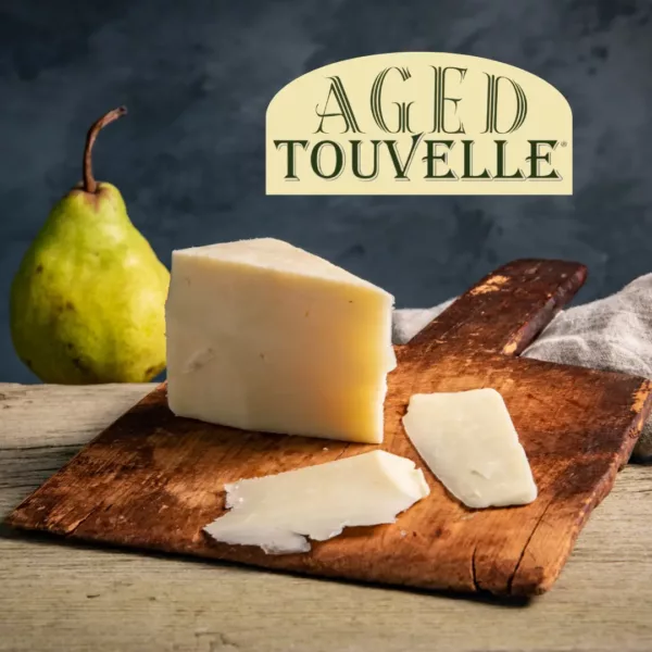 Aged Touvelle Reserve wedge on cutting board with pear